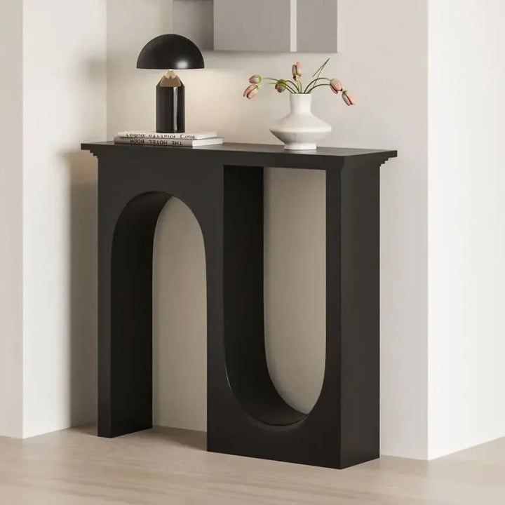 Modern black console table with decorative items against a neutral wall.